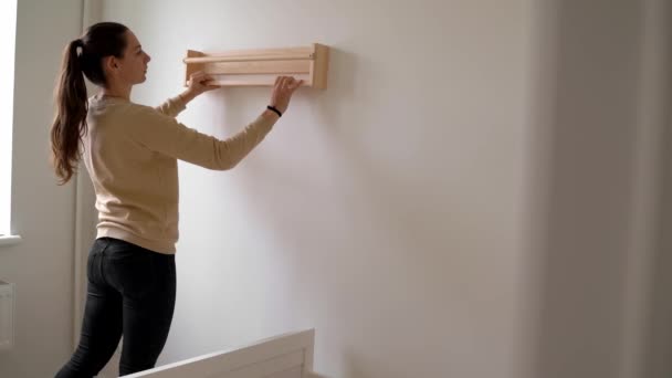 Ung kvinna renovering barnrum i nytt hus. Bokhylla av trä. Neutral barnkammare — Stockvideo