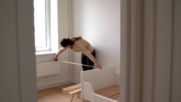 Mujer joven renovación habitación infantil en casa nueva. Estantería de madera. Vivero neutro — Vídeos de Stock