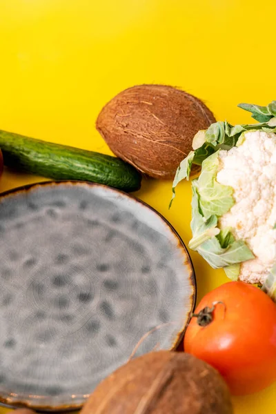Keramikgrau leere Plattenoberseite auf gelbem Hintergrund. viel Obst und Gemüse. Veganes Essen — Stockfoto