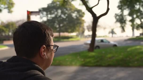 Close up portrait of walking man with wireless earphones. Listening to music or podcast on stroller walk — Stock Video