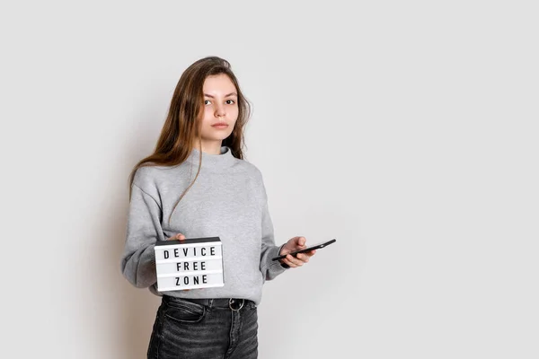 Menina cansada infeliz com smartphone e lightbox nas mãos. Conceito de zona livre de dispositivos. Desligar. — Fotografia de Stock