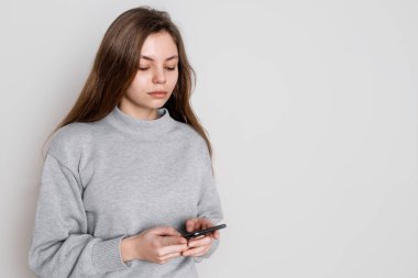 Stüdyoda beyaz arka planda akıllı telefon kullanan neşeli genç bir kadın. Milenyum konsepti. Sosyal medya