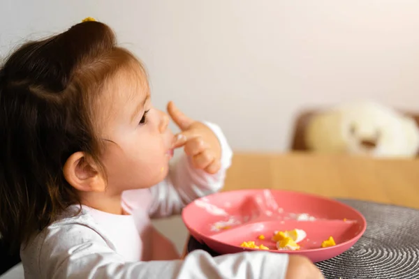 Bebê criança menina come seu almoço na cozinha com colher. Mãos sujas — Fotografia de Stock