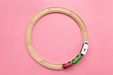 Top view of circle wooden railway and train on pink background