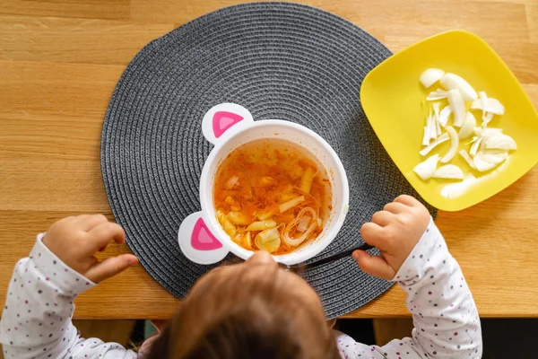 Bebê criança come sopa e cebola fresca para o almoço em casa . — Fotografia de Stock