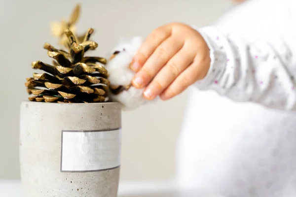 Bebé niño decoración de la mano con cono de pino dorado. Navidad. Juguetes naturales Waldorf —  Fotos de Stock