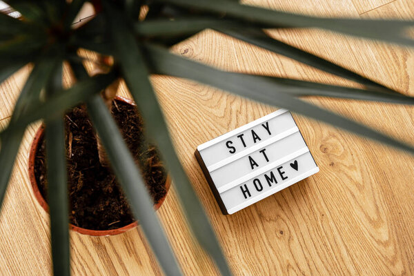 Lightbox with Stay home text on wooden background. Top view flat lay Covid-19 quote