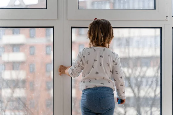 창문 근처에 서서 밖을 보고 있는 갓난아기 아기. 실내 경기 — 스톡 사진