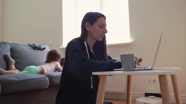 Fiatal nő, aki otthonról dolgozik. A gyerek rajzfilmeket néz a tablettán. Otthoni munka — Stock videók
