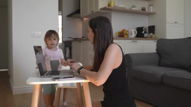 Fiatal nő, aki otthonról dolgozik kisgyerekkel. Boldog anyák otthoni irodája — Stock videók