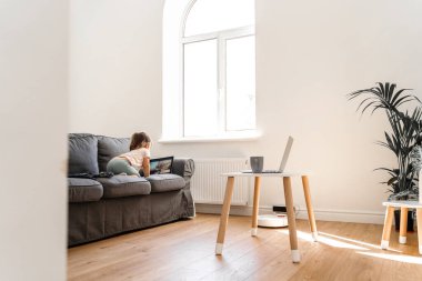 Oturma odasında bebek kanepede çizgi film seyrediyor.