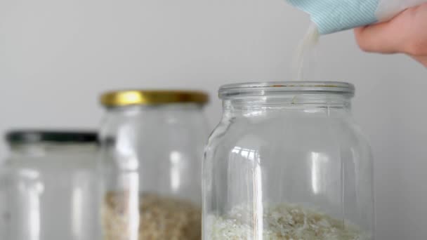 Close up of woman pouring rice into glass jar. Zero waste concept. Stay home stocks — Stock Video