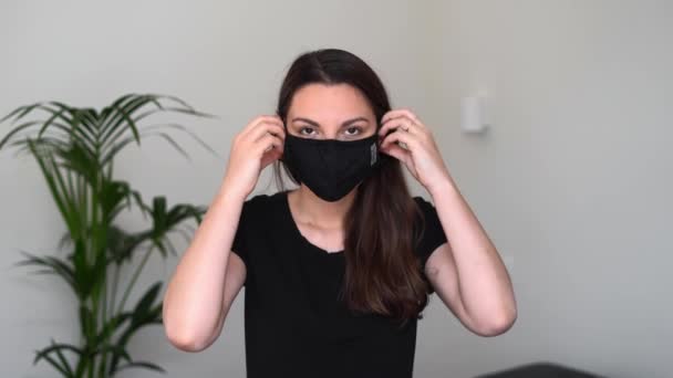 Poltawa, Ukraine - 27. März 2020 Junge Frau setzt schwarze Schutzmaske auf. Grippe- oder Virenpandemie. Allergie-Saison — Stockvideo