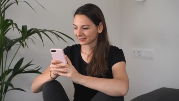 Mujer joven usando el teléfono móvil en casa. Feliz chica caucásica influencer . — Vídeo de stock
