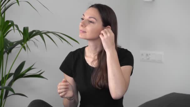 Joven mujer caucásica meditando con auriculares inalámbricos en casa. Ocio casero. Estilo de vida consciente — Vídeo de stock