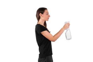 Elinde sprey plastik şişeyle temizlik sıvısı tutan genç bir kadın. Bahar temizliği konsepti. Dezenfekte ediliyor