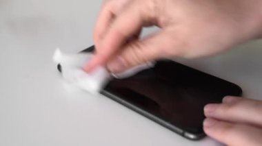 Antibakteriyel mendille telefon ekranını temizliyorum. Covid-19 virüs yayılmasını önlüyor. Kişisel modern hijyen