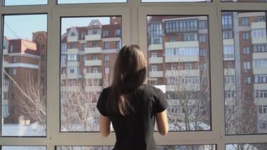 Genç kadın temiz hava ve D vitamini almak için balkon pencerelerini açıyor.