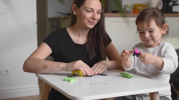 Çocuğuyla evde hamur oynayan genç bir anne. Bebekle ev aktivitesi. Aile zamanı. — Stok video