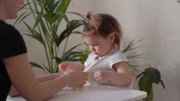 A kislány és az anya a sárga nyálkával játszanak. Otthoni aktivitás kisgyermekek otthon. Motoros készségek fejlesztése — Stock videók