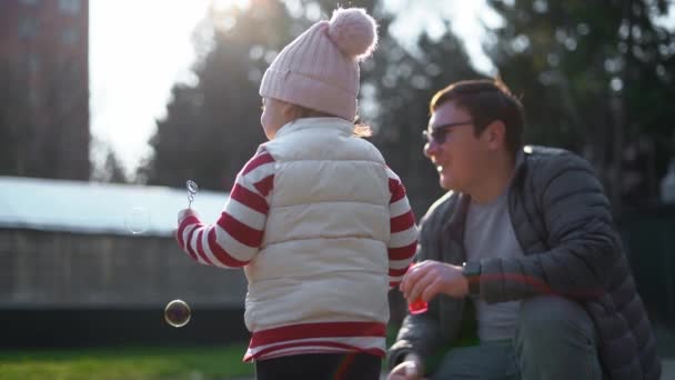 Hombre caucásico con su hijo soplando burbujas de jabón afuera. En cámara lenta. Actividad de fin de semana con niño pequeño, patio trasero — Vídeo de stock