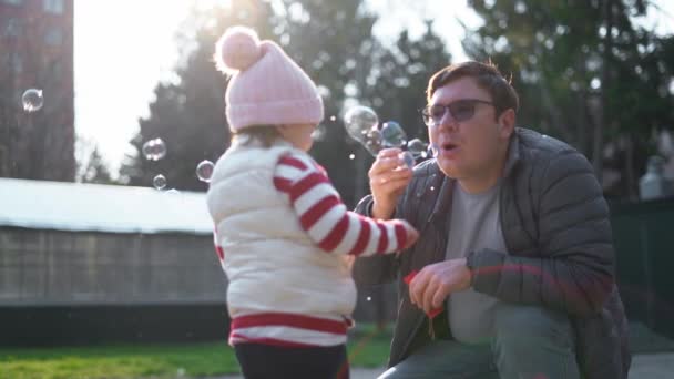 子供を持った白人男性が外で泡を吹いている。スローモーション。幼児、裏庭での週末の活動 — ストック動画