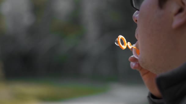 Young caucasian man blowing soap bubbles outdoors. Childish Happiness concept. — Stock Video