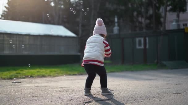 Szczęśliwy maluch bawiący się bańkami mydlanymi na podwórku. Beztroskie dzieciństwo wolności. — Wideo stockowe