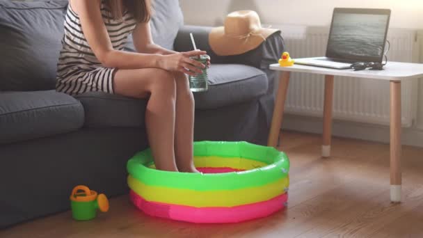 Buffo isolamento estivo a casa causato dalla quarantena del coronavirus. Giovane donna con piscina per bambini e schermo portatile con onde — Video Stock