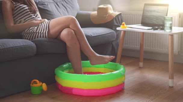 Забавна літня ізоляція будинку, спричинена карантином коронавірусу. Молода жінка з дитячим басейном і екраном ноутбука з хвилями — стокове відео