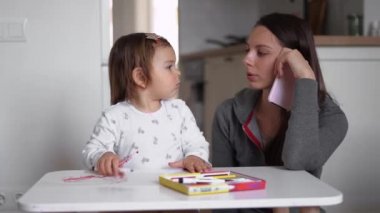 Küçük bir bebekle ev telefonunda çalışan genç bir anne anneye yakın oynuyor. Merkez, Covid-19 karantinası.