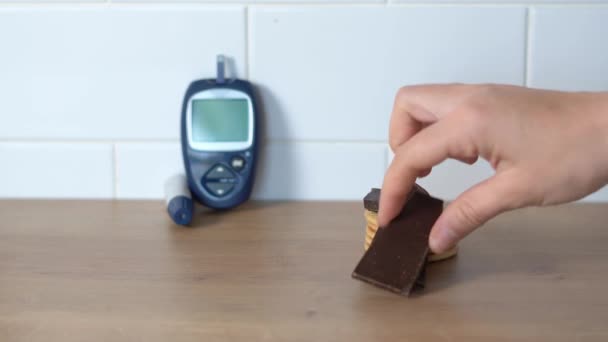 Met de hand snoepjes plukken op de keukentafel met Glucose meter op de achtergrond. Wereldwijd diabetesprobleem — Stockvideo