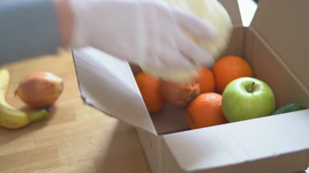Κοντινό πλάνο των γυναικών χέρια σε γάντια συσκευασίας κουτί με φρέσκα φρούτα και λαχανικά. Online παράδοση αγορών σούπερ μάρκετ — Αρχείο Βίντεο