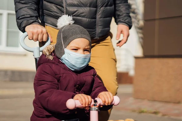 Junger Vater mit Kind auf Motorroller geht in medizinischen Masken nach draußen. Luftverschmutzung, Pandemie — Stockfoto