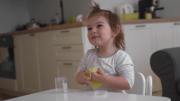 Повільний рух відео дівчинки малюка, яка грає жовтий слиз вдома. Діяльність для дітей. Ремесло для домашнього господарства — стокове відео