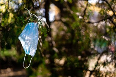Dışarıdaki ağaçta tıbbi maske. Covid-19 karantinasından kaynaklanan kirlilik