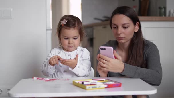 Jong moeder werken vanuit huis vorm telefoon met kleine peuter spelen in de buurt van mama. Binnenlandse Zaken, quarantaine Covid-19 — Stockvideo