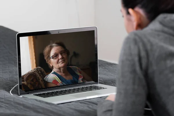 Evde yaşlı bir kadınla görüntülü konuşma yapan genç bir kadın. Uzaktan ilaç, hemşire, teknik danışmanlık.