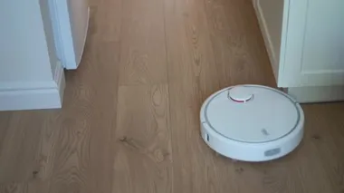 Beyaz robot süpürgesi evde yerleri temizliyor. Akıllı ev konsepti. Gelecekteki ev halkı.