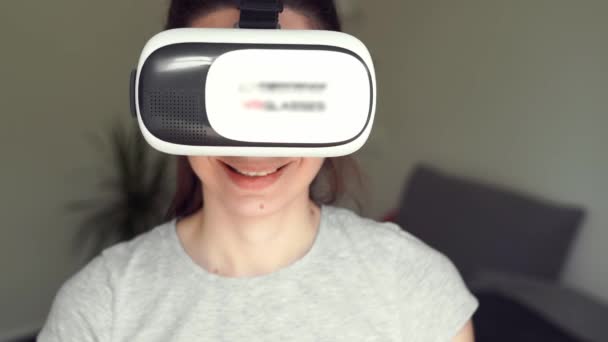Młoda kobieta siedzi w sypialni w okularach VR i używa AR do rozrywki, edukacji, nauki, zakupów — Wideo stockowe