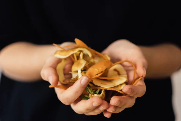 Siyah arka planda gübre kabukları olan elleri kapatın. Organik atık, toprak için gübre.