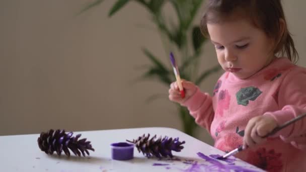 Vista superior de cerca de la mano del bebé haciendo lío con pintura púrpura en la mesa . — Vídeos de Stock