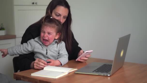 Stresszes fiatal nő, aki otthonról dolgozik kisgyerekkel. Egyedülálló anya otthoni irodája — Stock videók