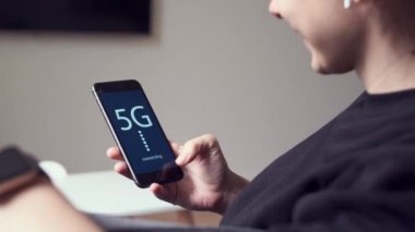 Ekranda 5G mesajı olan telefonu kullanan bir kadın. Hızlı mobil ağ