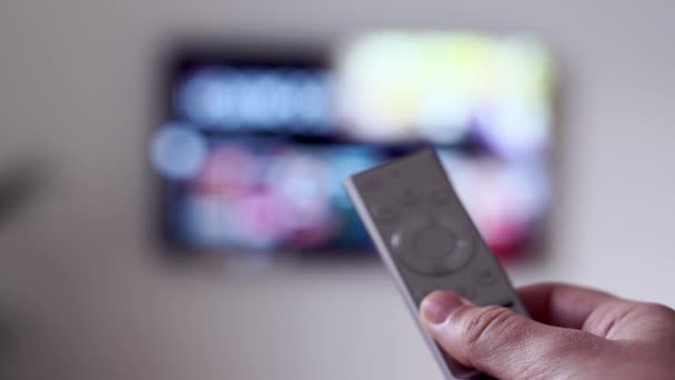 Mujer sentada en el sofá en la sala de estar con control remoto de televisión y viendo la plataforma de transmisión en línea VOD — Vídeos de Stock