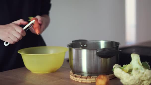 Mujer joven milenaria cocinando comida, pelando zanahoria en la cocina casera. Economía circular, alimentos reales, residuos orgánicos — Vídeo de stock