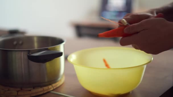 Mujer joven milenaria cocinando comida, pelando zanahoria en la cocina casera. Economía circular, alimentos reales, residuos orgánicos — Vídeo de stock