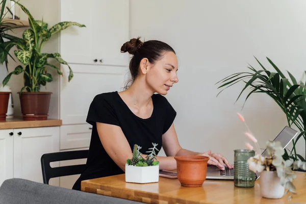 Millennial flicka arbetar hemifrån i ett växtrum. Frilans florist, ung företagare, hem trädgårdsskötsel — Stockfoto