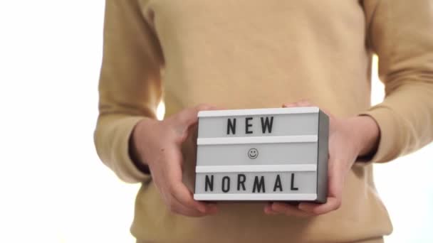 Woman holding lightbox with new normal text. post quarantine life, the end of covid-19 lockdown — Stock Video