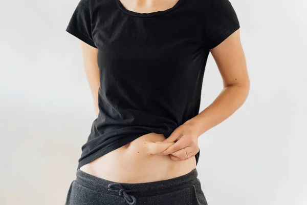 YOung woman holding her belly fat. Weight access, diabetic tummy. Postpartum figure